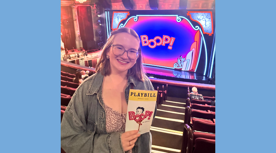 Maeve Sheehan '26GS holds a playbill for "Boop" while posing in front of the stage
